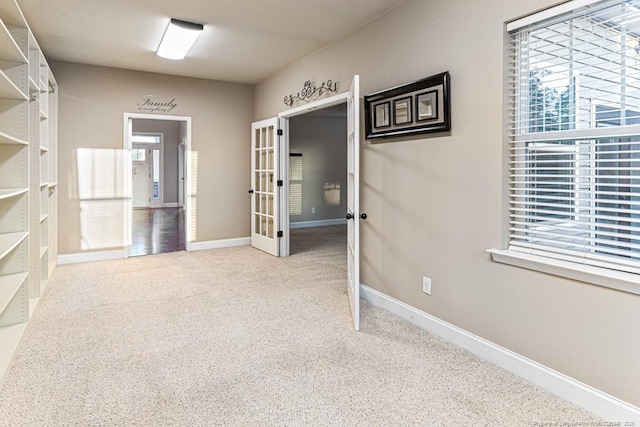 interior space featuring french doors, baseboards, a wealth of natural light, and carpet floors