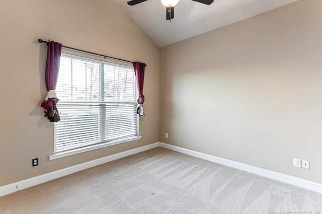 spare room featuring baseboards, light carpet, a ceiling fan, and vaulted ceiling