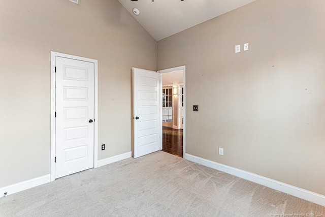 unfurnished bedroom featuring baseboards, carpet, and high vaulted ceiling