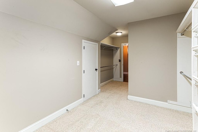 unfurnished bedroom with a walk in closet, baseboards, carpet floors, and a closet