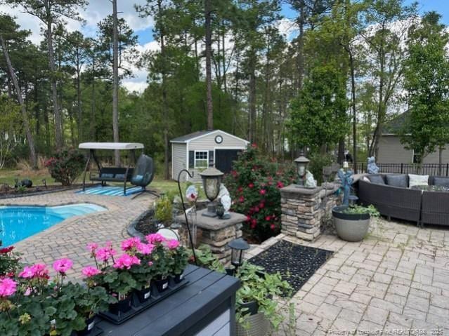 view of patio / terrace featuring a shed, an outdoor living space, an outdoor pool, and an outdoor structure