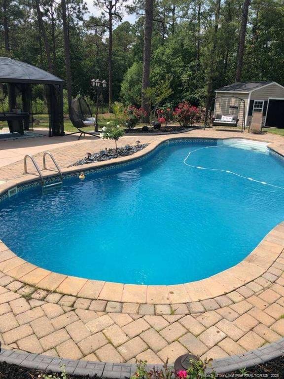 pool featuring a gazebo, an outbuilding, and a patio area