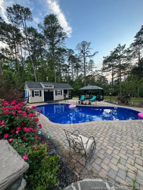 outdoor pool featuring a storage structure, a gazebo, an outdoor structure, and a patio area