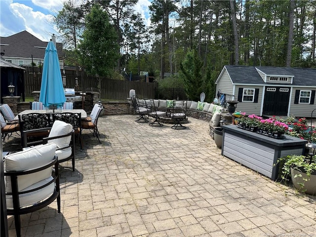 view of patio / terrace featuring outdoor dining space, an outbuilding, fence, and an outdoor living space with a fire pit