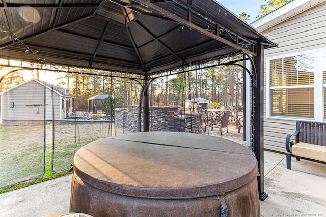 view of patio / terrace with a gazebo, outdoor dining space, and an outbuilding