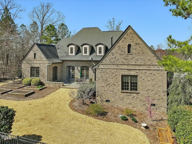 view of front of property featuring french doors, brick siding, a front lawn, and a patio area