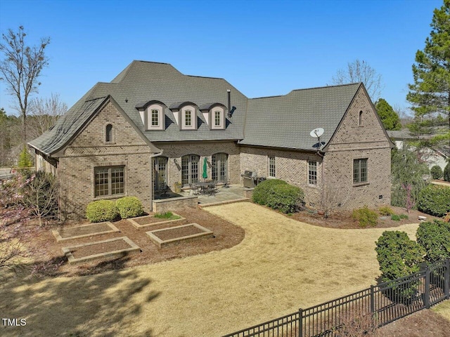 view of front of home featuring a patio, brick siding, and fence