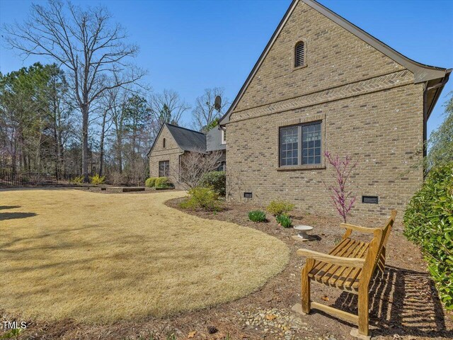 view of side of property with a lawn, brick siding, and crawl space