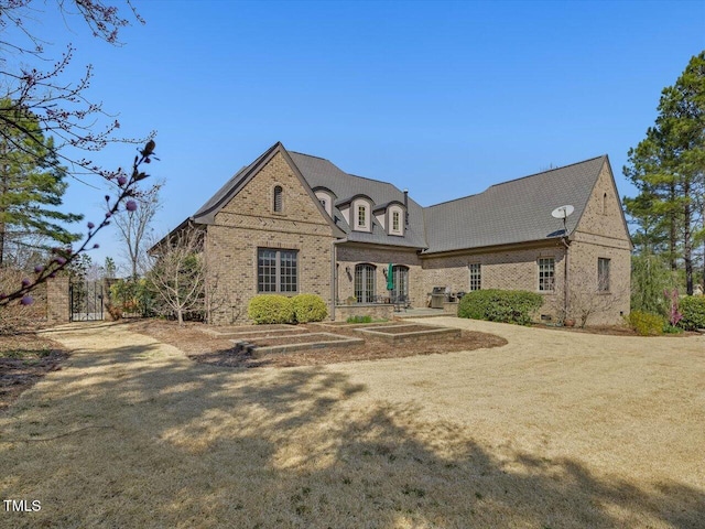 french provincial home featuring brick siding