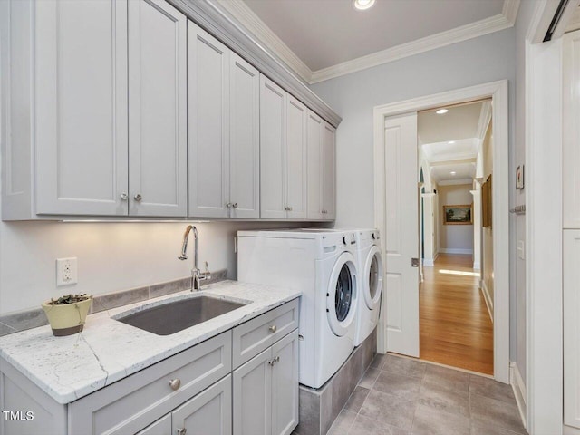 clothes washing area with a sink, washing machine and dryer, recessed lighting, cabinet space, and crown molding