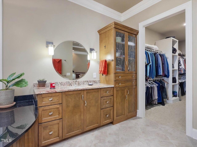 bathroom with tile patterned flooring, a walk in closet, vanity, and crown molding