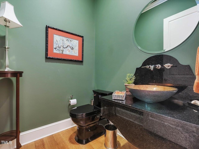 bathroom featuring baseboards, toilet, wood finished floors, and vanity