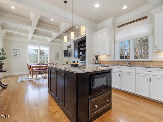 kitchen featuring black microwave, light wood-style flooring, coffered ceiling, white cabinetry, and a sink