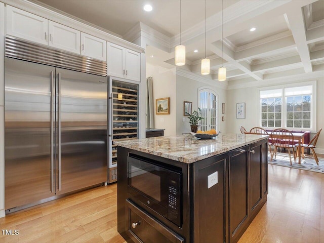 kitchen featuring coffered ceiling, light wood-style floors, built in appliances, white cabinetry, and beamed ceiling