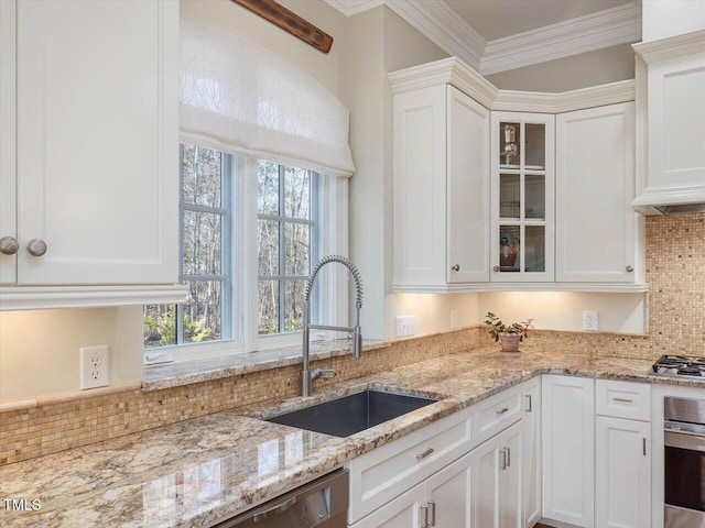 kitchen with white cabinets, ornamental molding, stainless steel appliances, and a sink