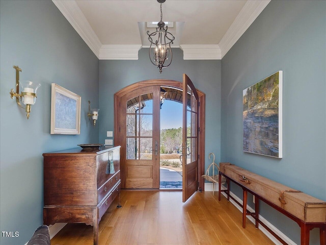 entryway featuring a chandelier, light wood finished floors, french doors, and crown molding