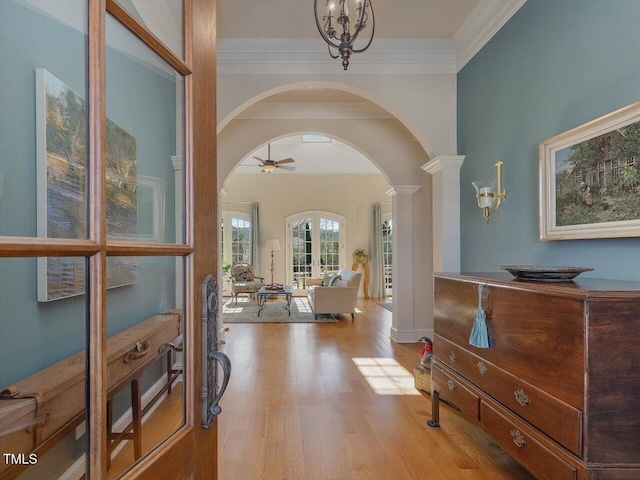 entrance foyer with arched walkways, ceiling fan with notable chandelier, ornamental molding, and wood finished floors