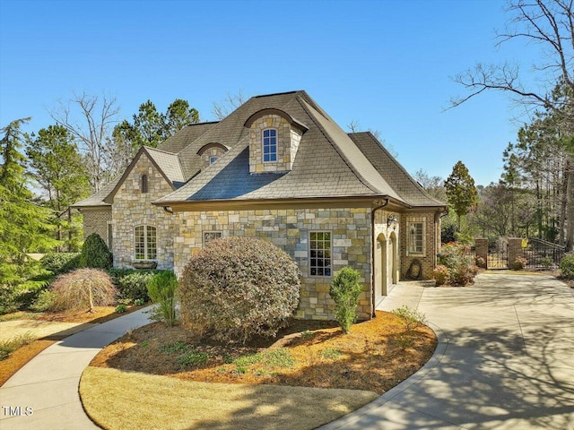 view of side of property featuring concrete driveway, an attached garage, and stone siding