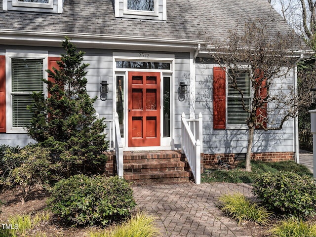 doorway to property with a shingled roof