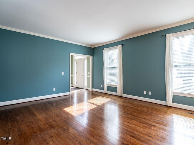 unfurnished room featuring wood finished floors, baseboards, and ornamental molding