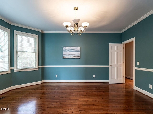 empty room with an inviting chandelier, crown molding, wood finished floors, and baseboards