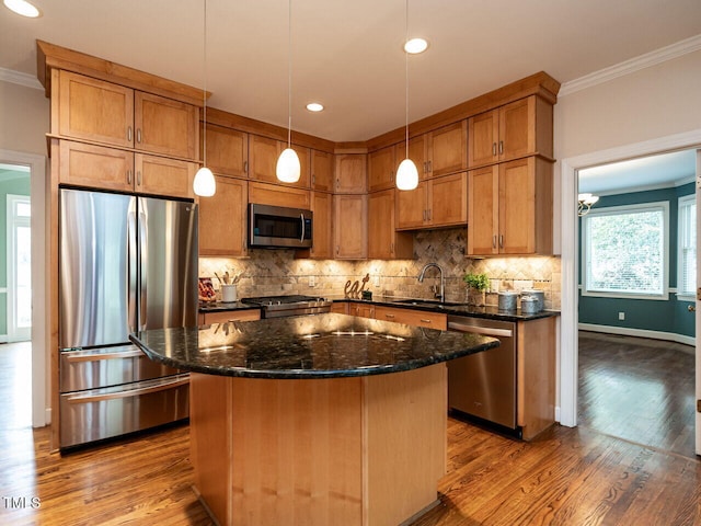 kitchen with a sink, stainless steel appliances, crown molding, backsplash, and a center island