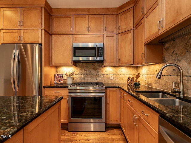 kitchen with a sink, stainless steel appliances, brown cabinetry, and decorative backsplash