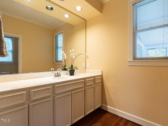 bathroom featuring vanity, wood finished floors, baseboards, recessed lighting, and ornamental molding