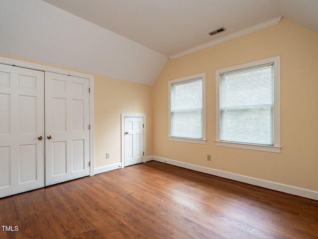 unfurnished bedroom with lofted ceiling, wood finished floors, baseboards, and visible vents