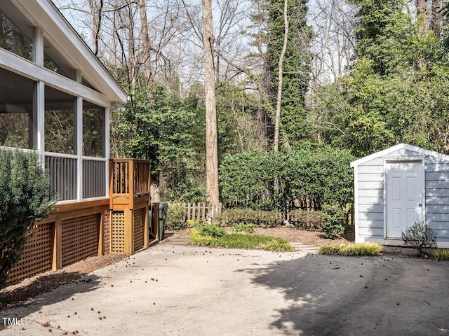 view of yard with an outbuilding, a shed, a patio, and a sunroom