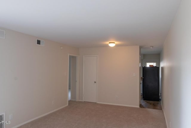 spare room with visible vents, baseboards, and light colored carpet