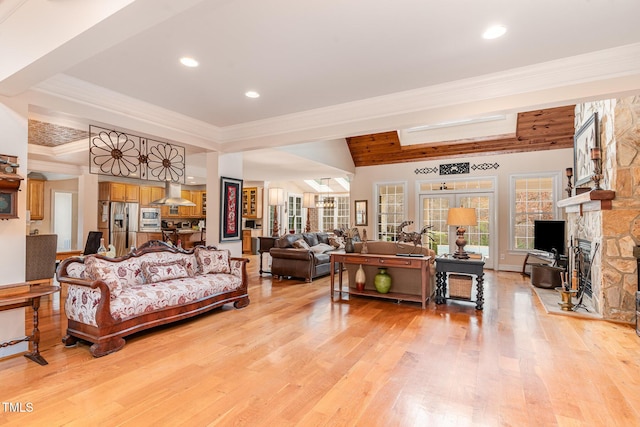 living room featuring recessed lighting, a stone fireplace, ornamental molding, and light wood finished floors