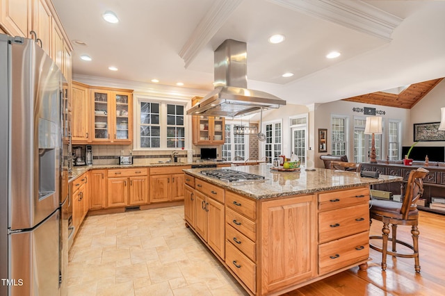 kitchen with open floor plan, a kitchen breakfast bar, island exhaust hood, stainless steel appliances, and a sink