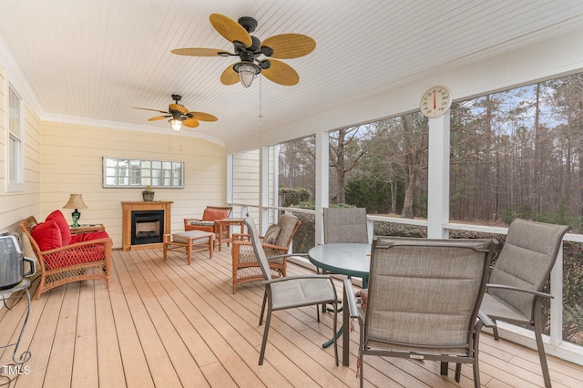 sunroom with an outdoor fireplace and a ceiling fan