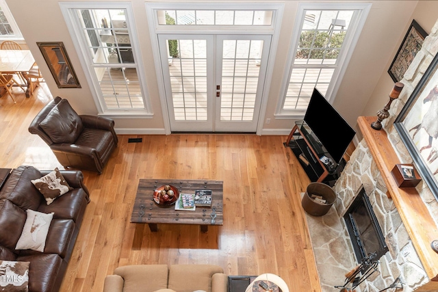 living area featuring visible vents, a fireplace, baseboards, and wood finished floors