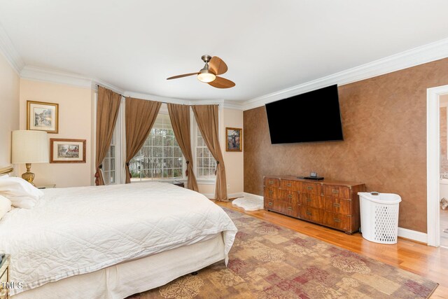 bedroom featuring baseboards, wood finished floors, crown molding, and wallpapered walls