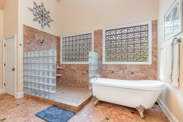 full bath with a freestanding bath, baseboards, a wealth of natural light, and walk in shower