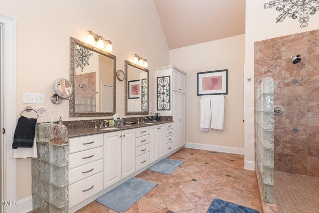 bathroom featuring a sink, double vanity, vaulted ceiling, and a walk in shower