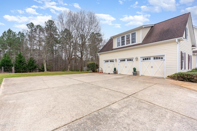 view of side of property featuring concrete driveway and a shingled roof