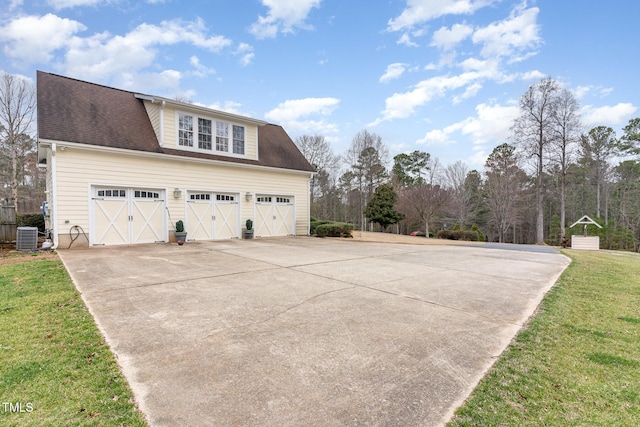 view of side of property featuring central air condition unit, a yard, roof with shingles, concrete driveway, and a garage