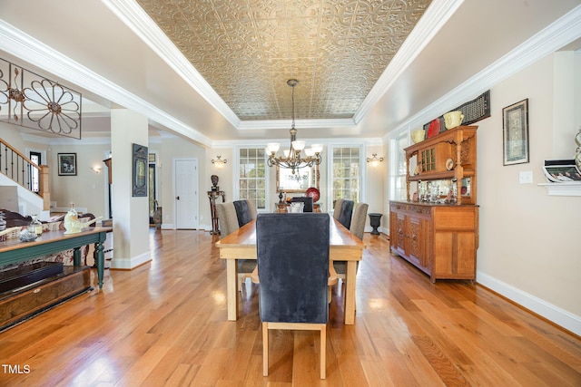 dining area featuring crown molding, baseboards, a notable chandelier, an ornate ceiling, and a raised ceiling