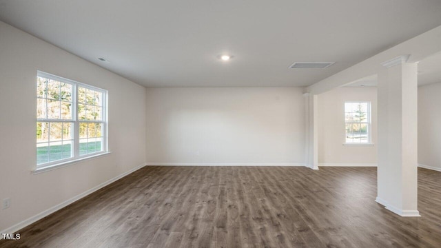 spare room featuring visible vents, decorative columns, baseboards, and wood finished floors