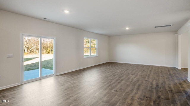 unfurnished living room featuring baseboards, visible vents, and dark wood-style flooring