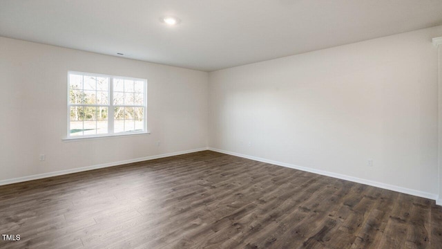 empty room featuring baseboards and dark wood-style flooring