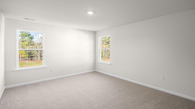 carpeted spare room with a healthy amount of sunlight, visible vents, and baseboards