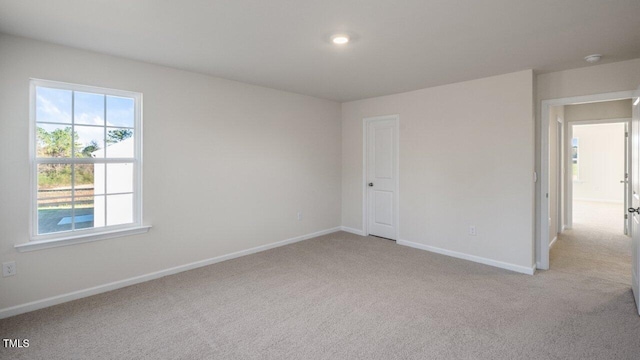 empty room featuring light colored carpet and baseboards