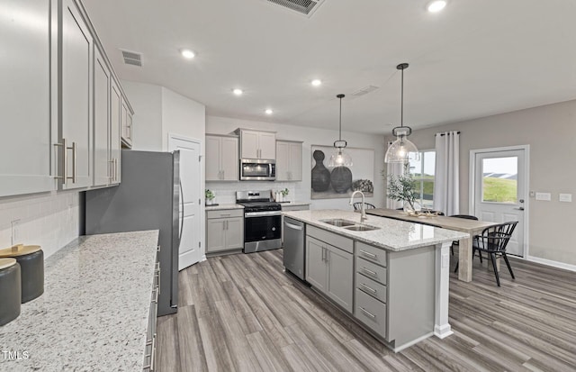 kitchen with visible vents, gray cabinetry, a sink, appliances with stainless steel finishes, and light wood finished floors