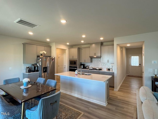 kitchen featuring visible vents, gray cabinetry, a sink, stainless steel appliances, and light wood finished floors