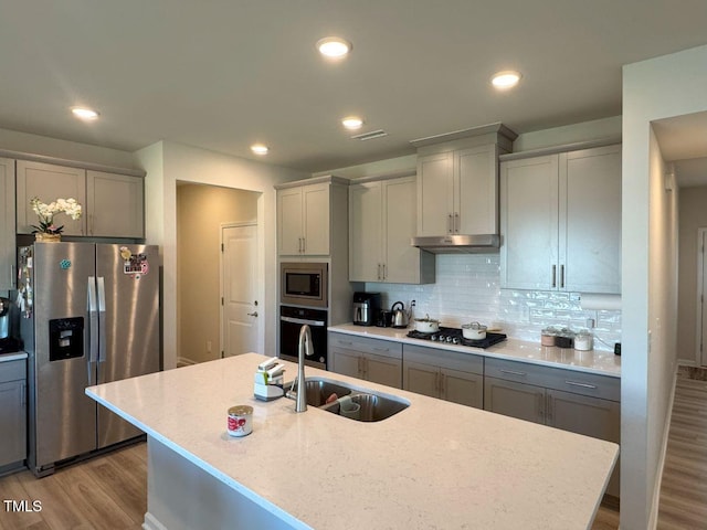 kitchen with a sink, appliances with stainless steel finishes, gray cabinets, and under cabinet range hood