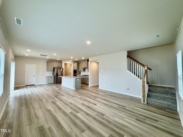 768 Riguard Way, Wendell, NC 27591 - unfurnished living room with stairway, light wood-style floors, recessed lighting, baseboards, and a sink